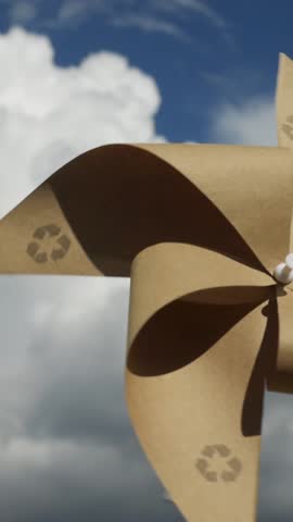 Recyclable Pinwheel is spinning against a bright blue sky vertical video. Pinwheel made from recyclable materials, symbolizing sustainability and eco-friendliness. Renewable energy concept
