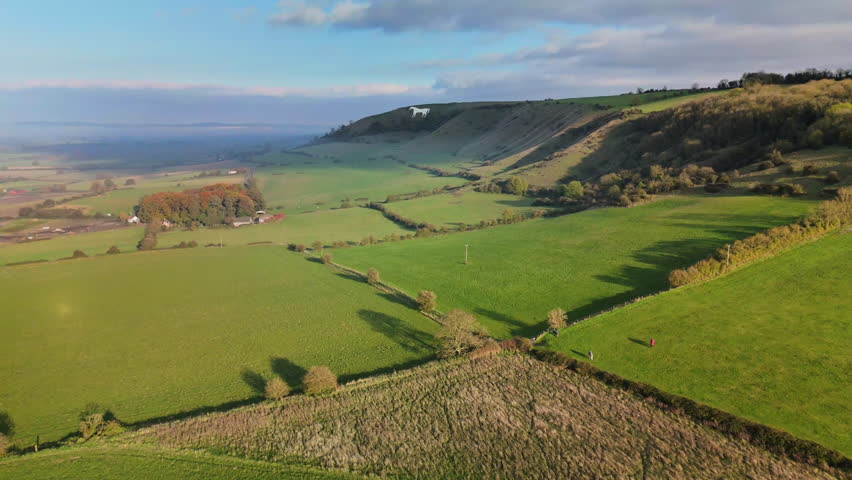 Aerial shot flying over rural English landscape towards Chalk Horse on hillside.