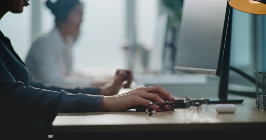 Modern call center office: Close up of Caucasian female technical support specialist working on computer, talking on headset. Multiethnic team of hotline operators providing online customer service.
