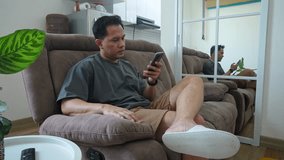 Adult Asian Male Turning Off Smartphone And Sleeping On Reclining Couch At Home - Powered by Shutterstock - Get 15% off with code: PIKWIZARD15