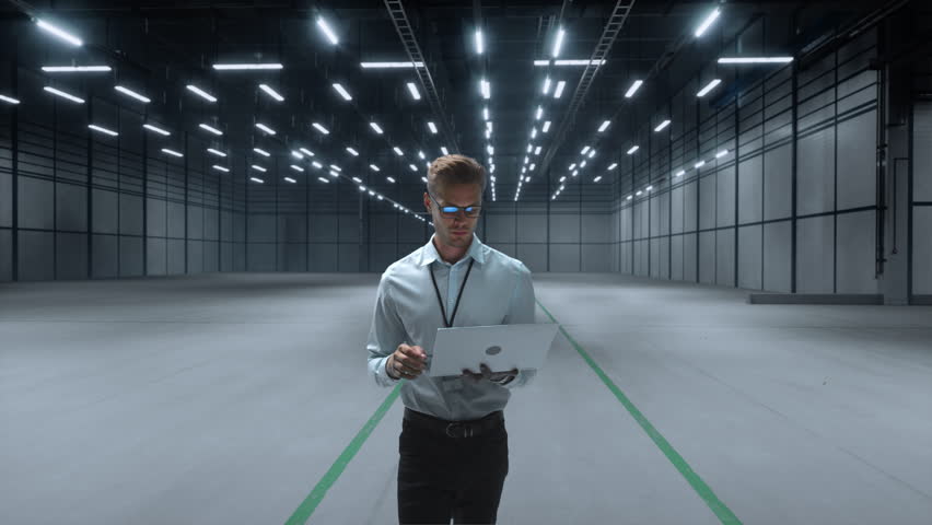 Technician Activates Futuristic Automotive Factory, Warehouse Construction of Robotic Arms and Vehicle Frames. Advanced Manufacturing Visualization Digital Twin Technology and Smart Production System