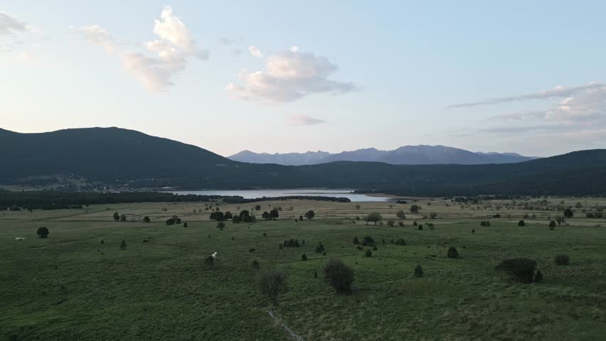 Experience the tranquil beauty of a vast landscape as the sun sets over a calm lake in Colorado. The mountains frame the scene, enhancing the serene atmosphere