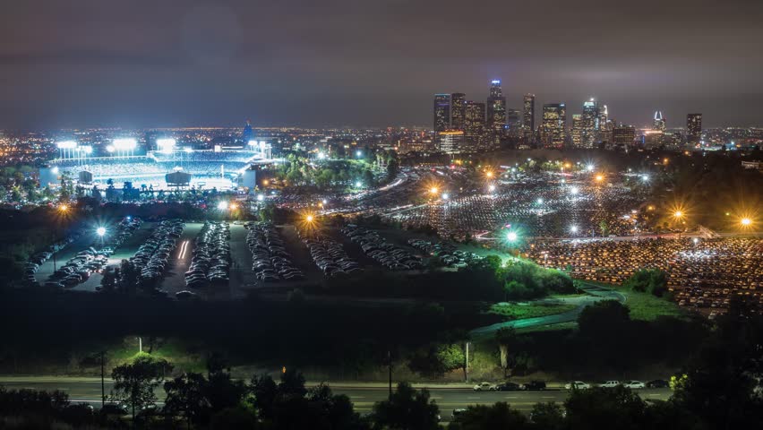 Time Lapse of huge parking lots emptying in Los Angeles at a sporting event. The downtown buildings of LA are in the background. 