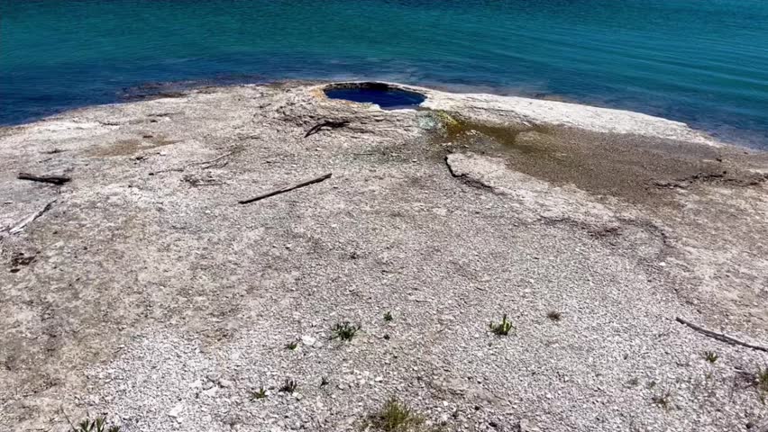 An effective and fantastic panning reveal of the serene blue waters and the fishing geyser hole of the West Thumb area in Yellowstone National Park.