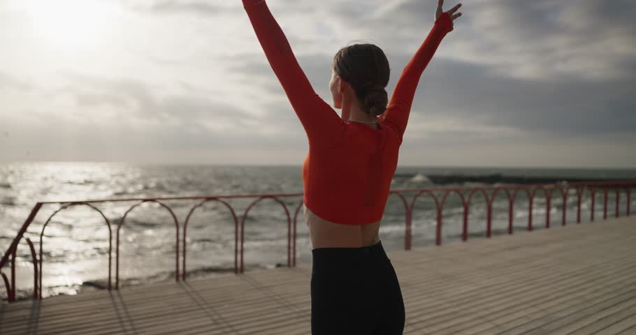 Girl yoga master meditates and folds her hands on the seashore in the summer morning