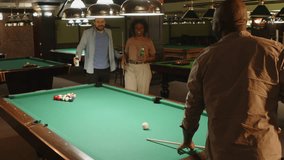 Back view of African American man aiming at cue ball while starting playing pool game with diverse friends in bar - Powered by Shutterstock - Get 15% off with code: PIKWIZARD15