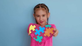 A girl shows a heart-shaped postcard with multicolored puzzle pieces for the day of awareness about autism - Powered by Shutterstock - Get 15% off with code: PIKWIZARD15