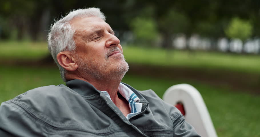 Senior man, happy and relax in park for retirement, positive mood and holiday with weekend break. Elderly person, smile and peace in nature for travel, vacation and pension fund with joy in Germany