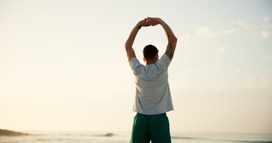 Man, fitness and stretching with back on beach for breathing exercise, warm up or outdoor workout in nature. Male person, yogi or zen with sunset for balance, health and wellness on ocean coast