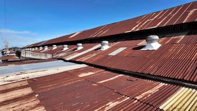 Rusty Corrugated Metal Roof with Ventilation Domes Under Clear Blue Sky, Showcasing Weathered Textures and Industrial Charm, Evoking Nostalgia and Resilience. - Powered by Shutterstock - Get 15% off with code: PIKWIZARD15