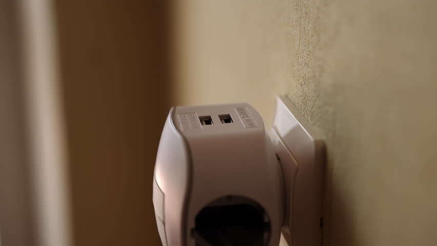Close-up cropped shot of male hand inserting usb cable into white wall socket adapter featuring two usb ports, providing convenient charging solution, closeup, unrecognizable person, slow motion.