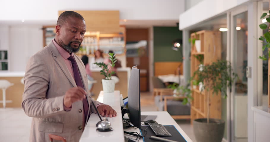 Frustrated, black man and reception with bell at hotel for assistance, delay or waiting to check in. Angry, impatient and annoyed male guest at front desk of accommodation for bad hospitality service