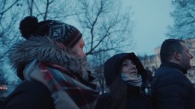 Couple and friends walking through Riga’s winter market in the evening, surrounded by leaveless trees and city lights and decorations at dusk - Powered by Shutterstock - Get 15% off with code: PIKWIZARD15