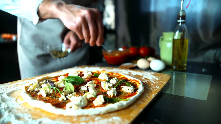 Preparing Pizza For Baking. Italian Pizzaiolo. Chef Make Pizza In Restaurant Kitchen. Tasty Pepperoni Pizza Making With Fresh Ingredients. Cheese Sprinkling During Pizza Making By Professional Cooks
