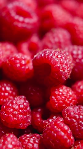 Heap of plump raspberries rotating. Delicious summer berries. Healthy organic nutrition. Vertical footage. Fresh red berries. Close-up in 4K, UHD