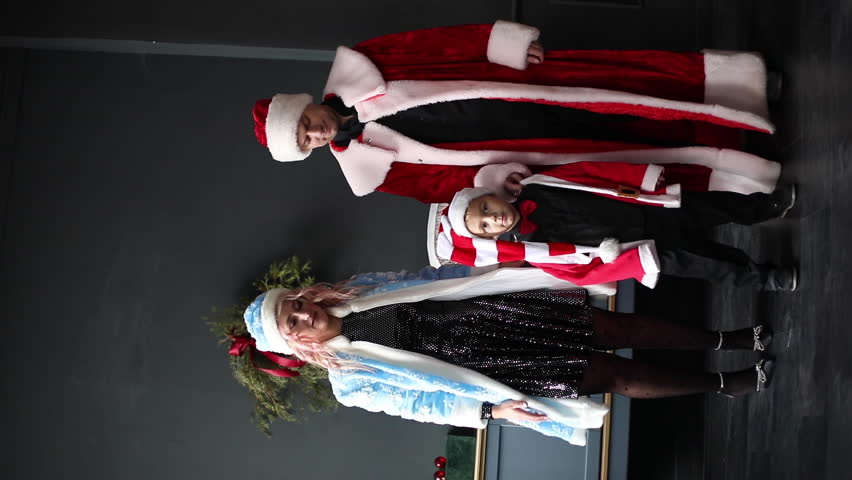 a family dressed as Santa Claus and snow maiden dances near the Christmas tree