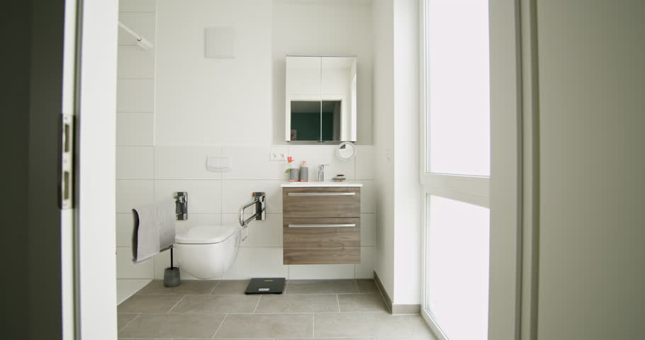 Contemporary bathroom with wheelchair accessible shower and modern vanity. White tiles and natural light create clean and bright space. Design includes accessible features for ease of use.