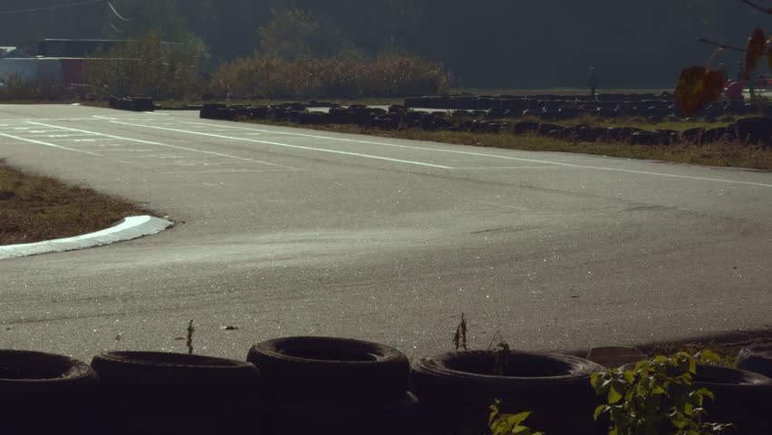 Karting competition on a racing track at sunset. Teenager riding a kart. Karting as a sport