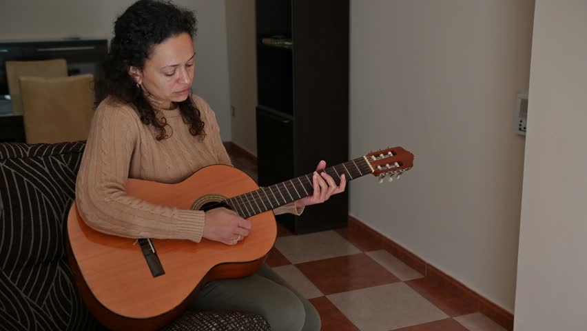 Woman playing acoustic guitar in cozy living room setting