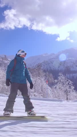 FIRST PERSON VIEW CLOSE UP: Female snowboarder riding fast down the ski slope leading through snowy forest in sunny mountains. Snowboarder girl having fun in idyllic mountain ski resort