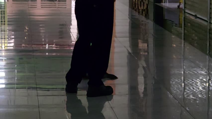 rear view of a janitor mopping the floor in the mall hallway.
