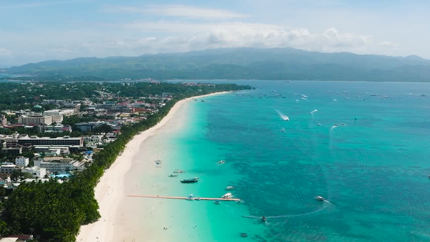 Tropical white sand beach with waves and boats over clear waters. Boracay Island. Philippines.