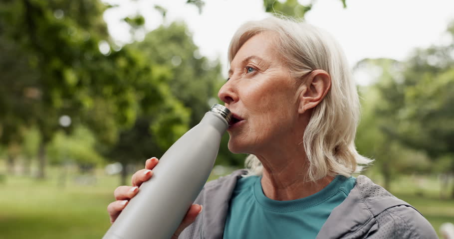Fitness, drinking water and senior woman in park for wellness, health and minerals in nature. Retirement, morning and mature person rest with liquid for cardio workout, training and exercise outdoors