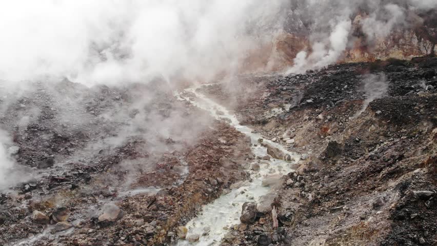 Mountine volcanic with holes between the rocks issuing gases and mountain river with hot sulfurous water