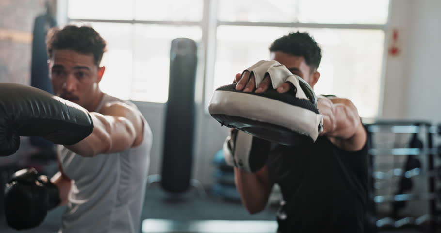 Athlete, boxing and coaching in gym for fitness, exercise and learning with help, workout and training. Men, boxer and personal trainer for sports, teamwork and growth with martial arts and fight