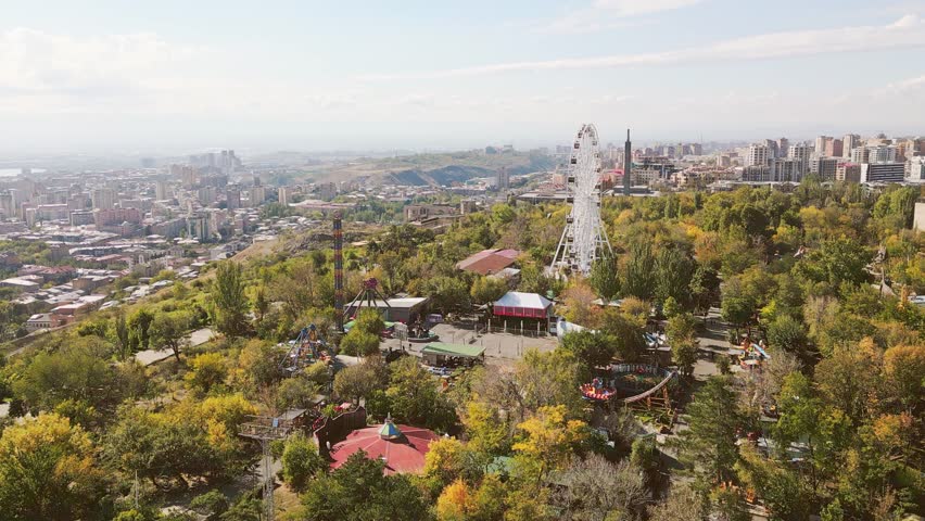 Yerevan, Armenia - 19th october, 2024: Aerial view visitors ride in carousels in amusement Victory Park in Sunny autumn day. Travel and things to do visit Yerevan concept