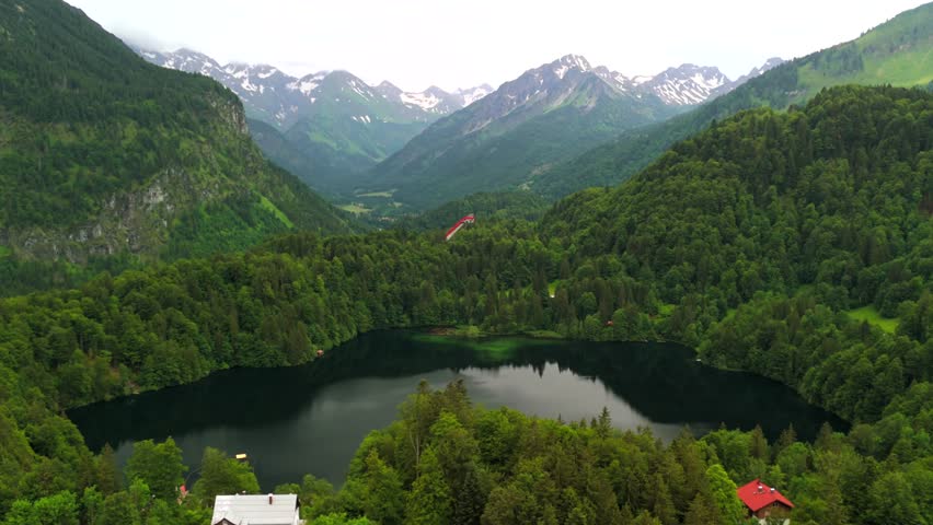 Drone views of Freibergsee and Heini-Klopfer- Schkiflugschanze in Bavaria, Germany. Surrounded by mountains and forests, this pristine lake and famous ski jump is an aerial view of area. Oberstdorf. 