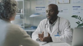 African American male doctor giving advice and shaking hands with grey-haired female patient during medical appointment in clinic - Powered by Shutterstock - Get 15% off with code: PIKWIZARD15
