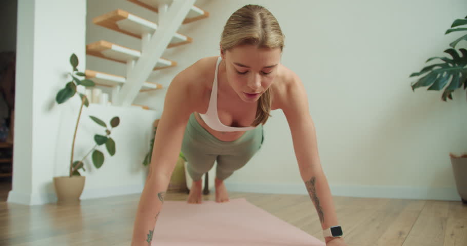 Focused Push-Up Pose Highlighting Strength and Form in a Minimalist Home Gym with Greenery, Emphasizing Upper Body Control and Core Engagement During Intense Workout