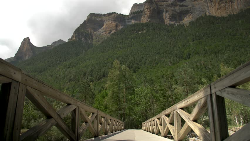 A young man crossing over a bridge while hiking in Ordesa y Monte Perdido National Park in the  Pyrenees in Spain.
