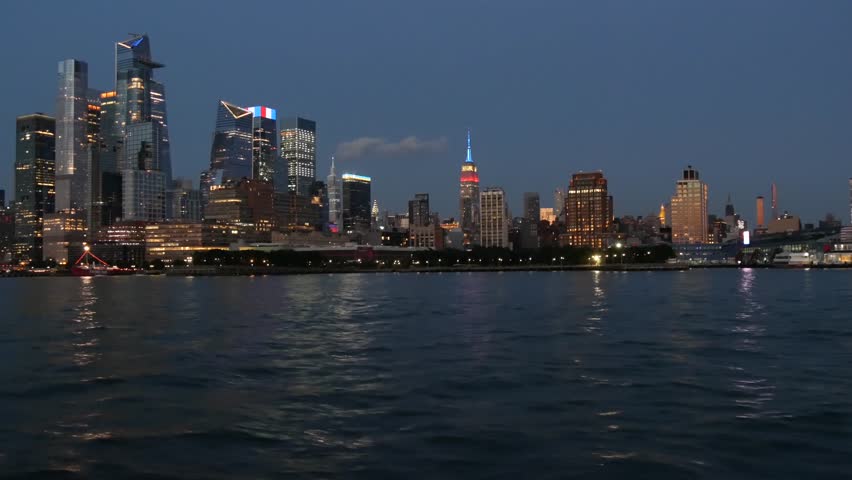 New York City skyline from river ferry boat. Manhattan Midtown, Hudson Yards skyscrapers from ferryboat. Waterfront panorama, riverfront architecture, USA. Evening dusk twilight. Empire State Building