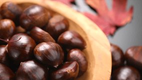 Chestnut, Fresh sweet chestnuts with autumn red leaves on black background, top view. Thanksgiving day. Edible chestnuts (Castanea sativa) rotating in wooden bowl. Top view. Close up.  - Powered by Shutterstock - Get 15% off with code: PIKWIZARD15