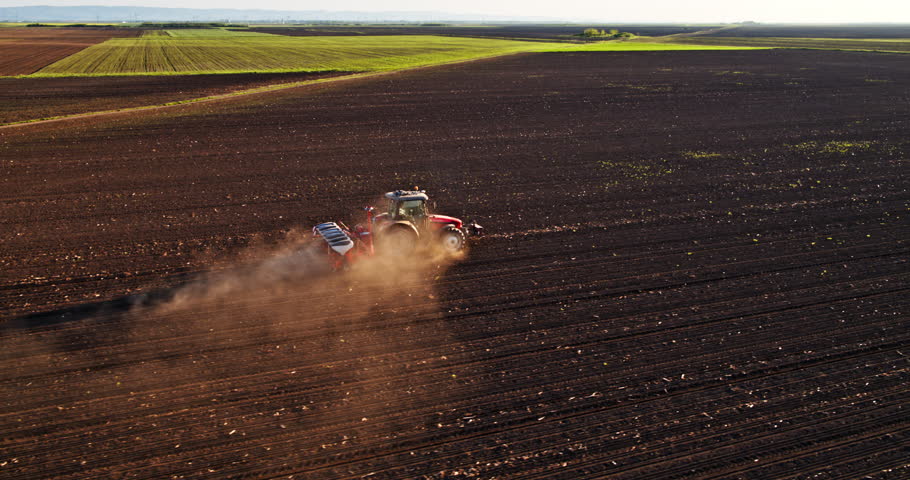An aerial shot of a farmer in tractor seeding soybean