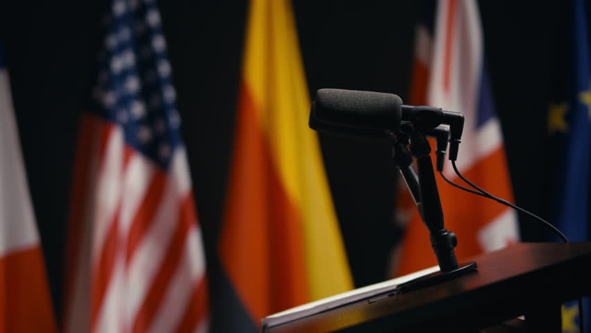 Rostrum with microphone at political summit, briefing room, flags background