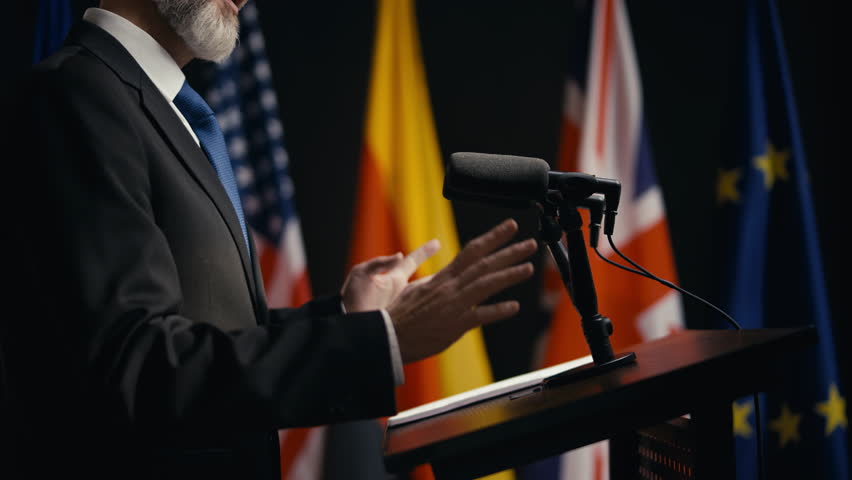 Diplomat speaking in microphone at rostrum, speech at international summit