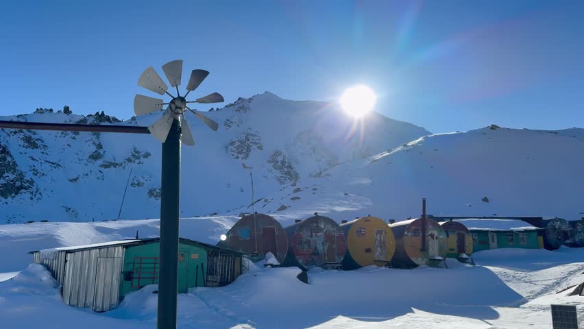 T1 mountain station located in the mountains of Zailiyskiy Alatau, Almaty, in winter. Sunlight shines over the snow-covered landscape, highlighting the rustic charm.