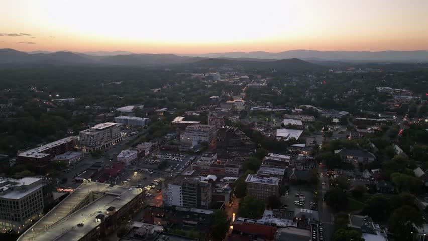 Charlottesville City at dusk. American downtown in Virginia State during golden sunset. Silhouette of mountain range in background. Drone top down shot.