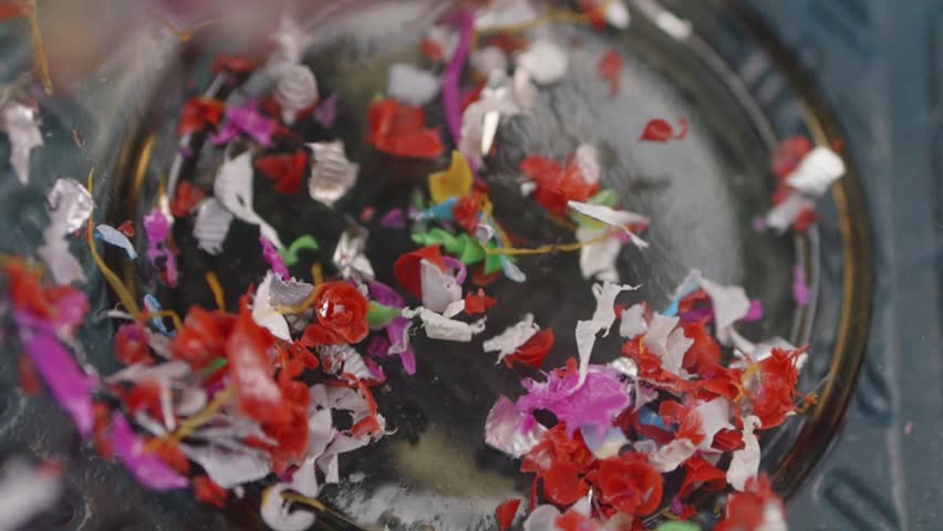 Microplastic particles fall into a sample container, colorful bits arranged by hand in slow motion. Environmental pollution lab study, macro shot.