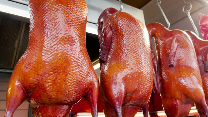 Hanging Peking Roasted Duck on Traditional Market. Beijing Grilled Duck on chinese food restaurant display cabinet. Concept for asian street food. In the background is a hieroglyph meaning Silver