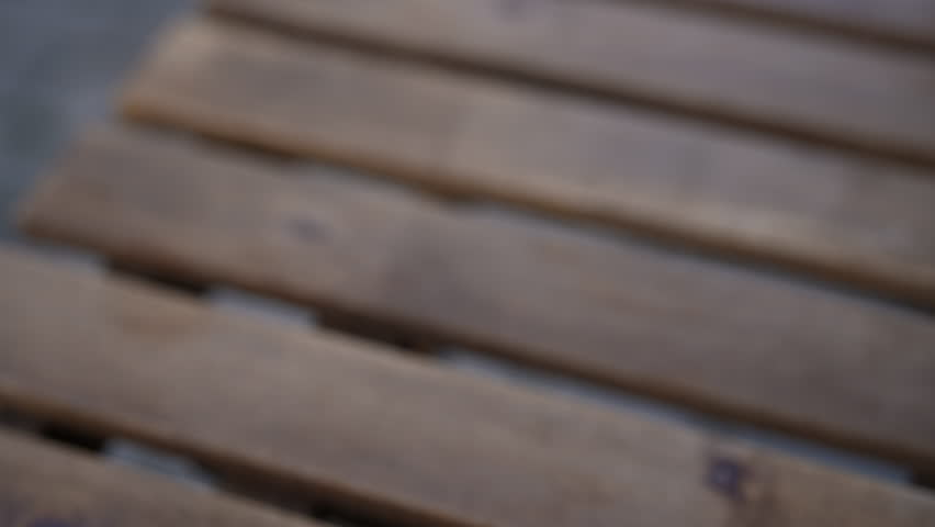 Close-up hands of unrecognizable man placing takeout cup of black coffee on wooden table, rich aroma of beverage fills air, perfect for morning break or casual moment of relaxation, slow motion.