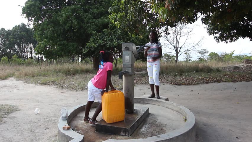 Young girls getting fresh water in the community hand water pump in rural Africa