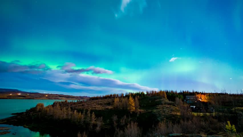 Shimmering aurora borealis or northern lights reflecting on Lagerfljot River, Egilsstadir, Iceland - time apse in autumn