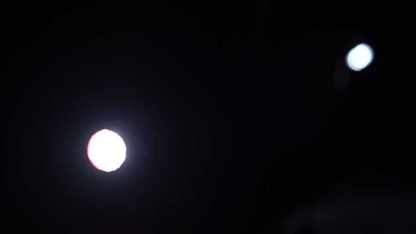 flashlight pointing at camera through darkness focusing and defocusing. 