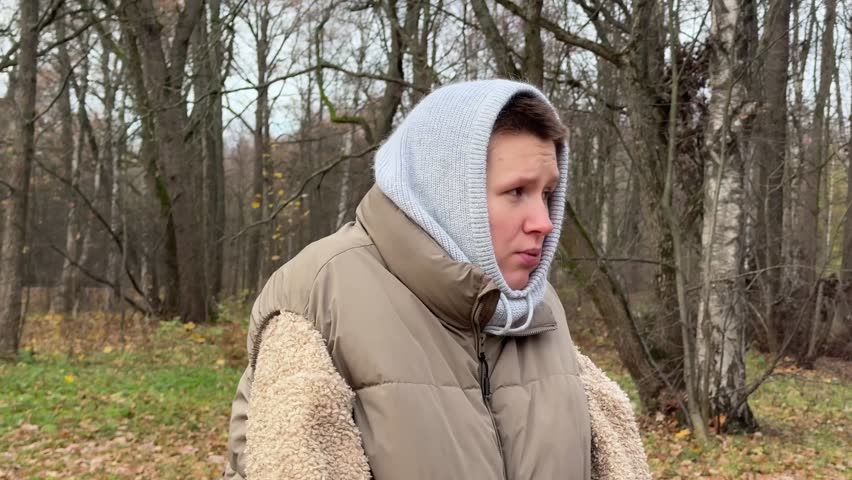 Frozen woman shivering and trembling because of cold weather in the park 
