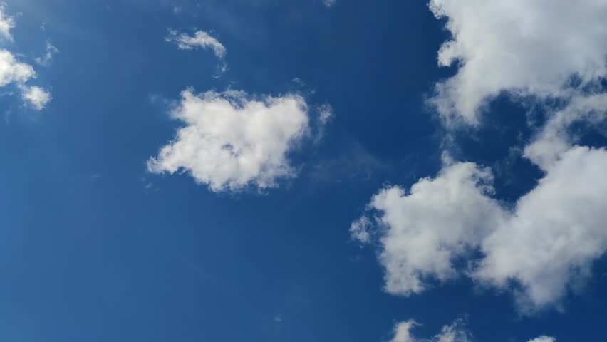 Cumulus clouds in the sky. The blue sky is mostly clear, with white clouds occasionally moving across the sky. They are located at different heights and change their shape and size as they move.