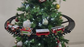 Toy Christmas train moving around a beautiful Christmas tree surrounded by colorful balls - Powered by Shutterstock - Get 15% off with code: PIKWIZARD15